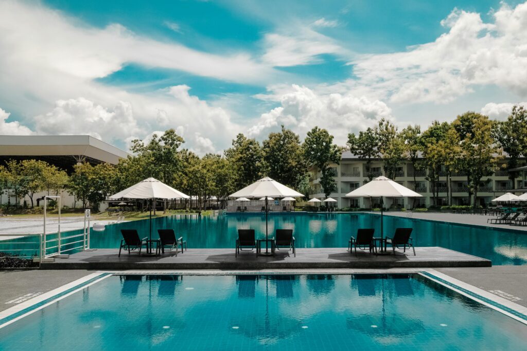 Explore a luxurious resort poolside with umbrellas and lounge chairs under a bright sky, perfect for summer vacations.